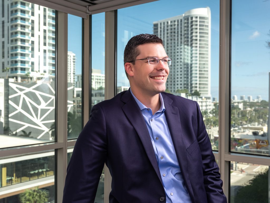 man in suit in from of glass windows with buildings in background