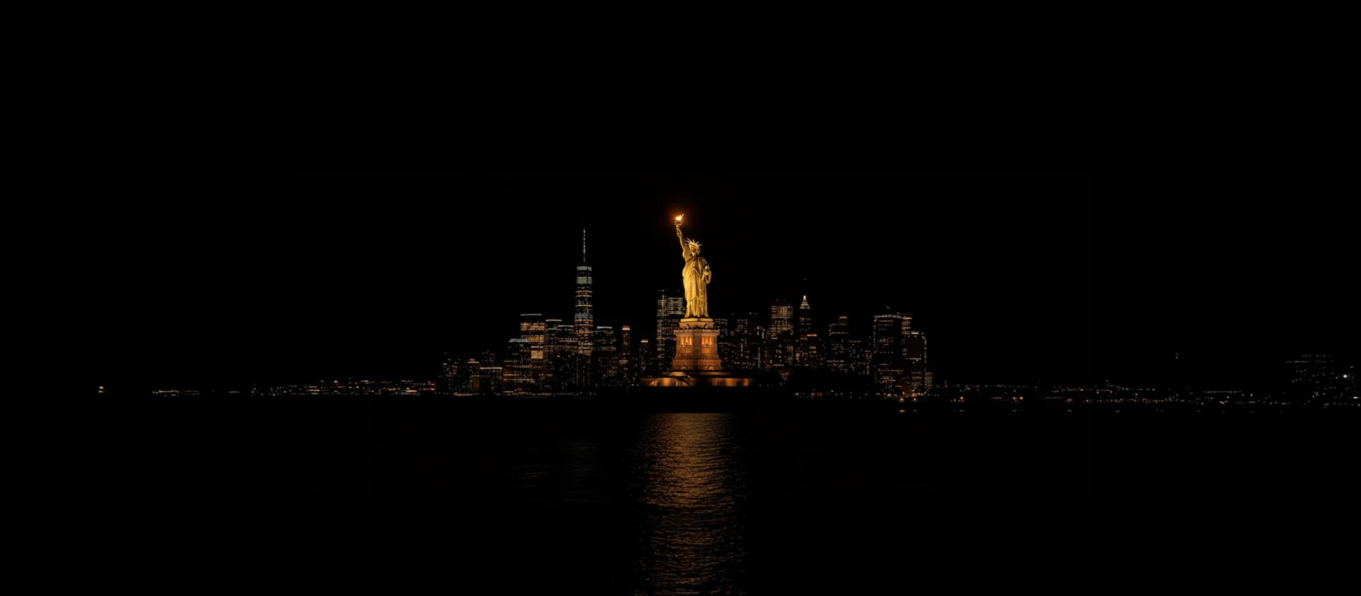 statue of liberty at night with new york city skyline in background
